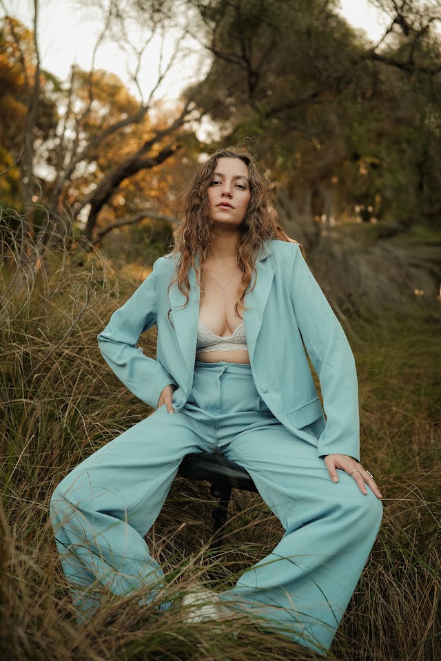 Model in a light blue pantsuit posing in nature, representing garden-inspired fashion 2025 with botanical style, pastel fashion trend, and eco-friendly style.