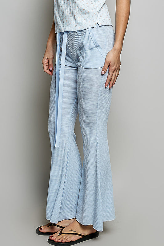 Side view of textured ribbed knit flare pants showing flared leg silhouette and functional pocket detail