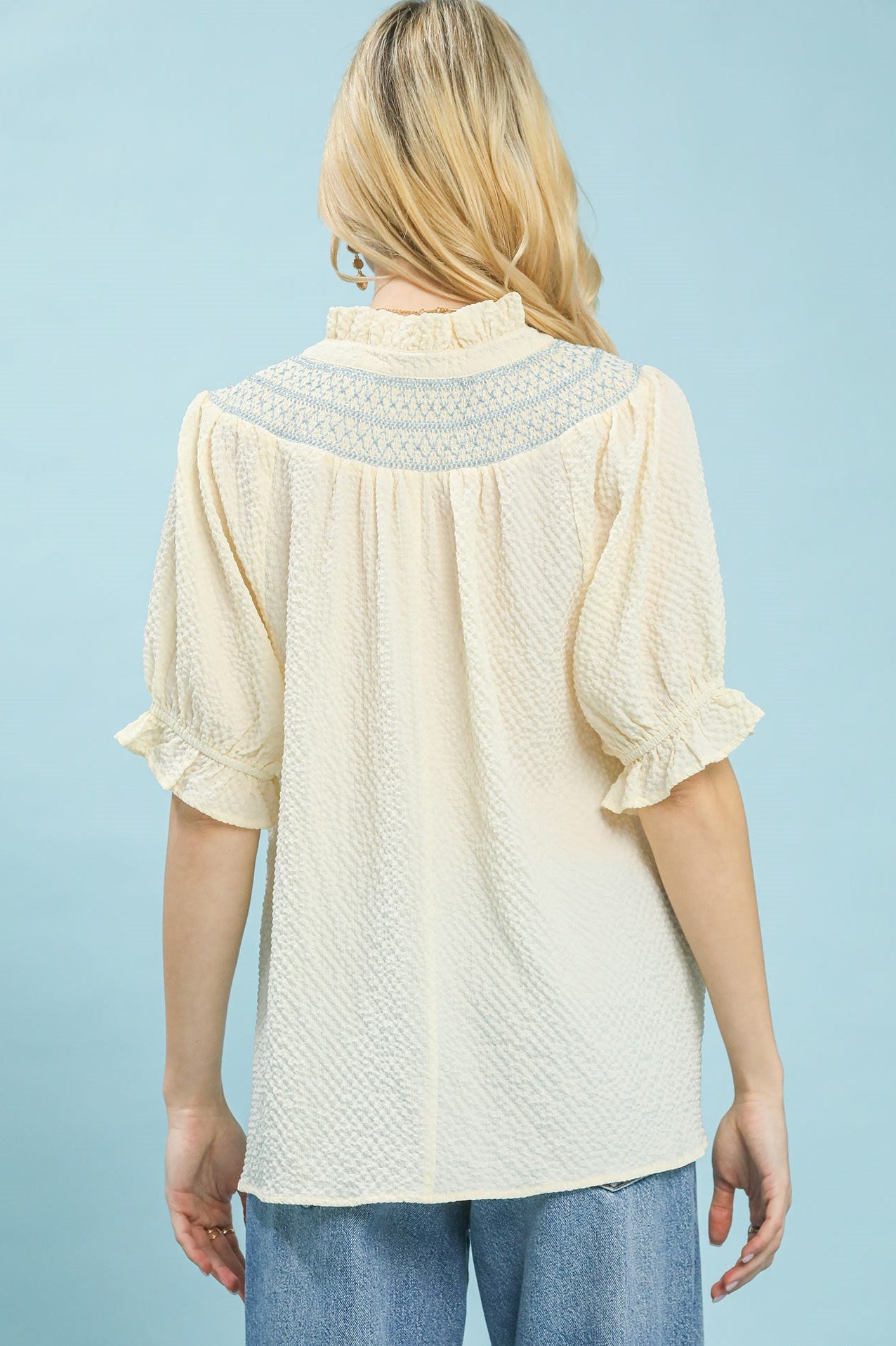 Back view of textured Henley blouse featuring lace shoulder details and relaxed flowy fit