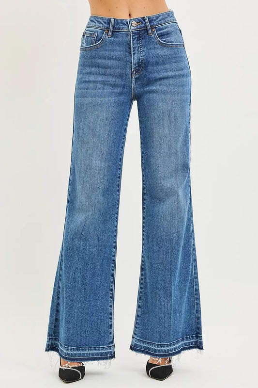 Front view of high rise wide leg jeans with released hem, model walking with hands in pockets, showing relaxed fit and 32.5 inch inseam, cotton lyocell denim