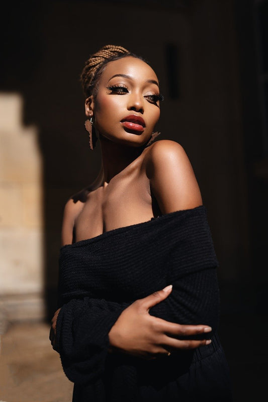 Woman wearing an off-shoulder black top showcasing effortless feminine fashion with a confident, modern style in soft natural lighting