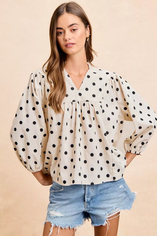 Model standing straight on in polka dot corduroy blouse, v neckline, quarter sleeves hitting mid forearm, no stretch structured fit, playful retro print