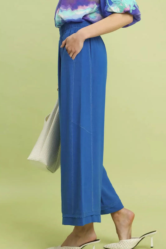 Side profile of Centprime Umgee linen pants showing flowy wide leg silhouette, elastic waistband, and contrast stitching in sage green