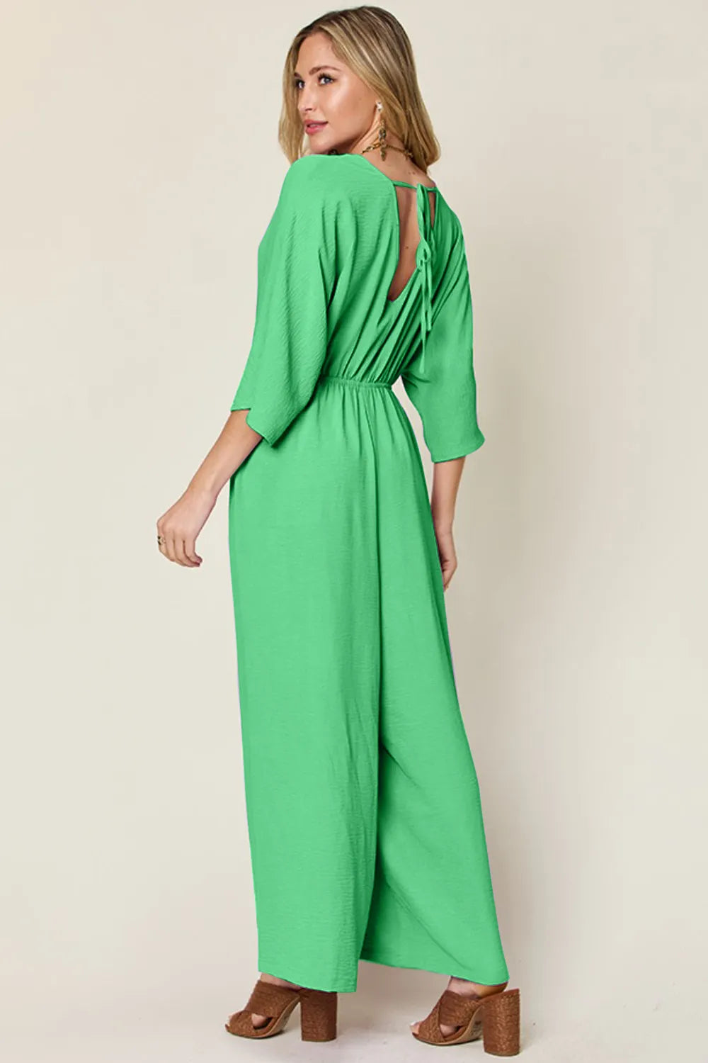 Double Take Full Size Surplice Wide Leg Jumpsuit with Pockets back view model posing, showing fabric movement and full length silhouette