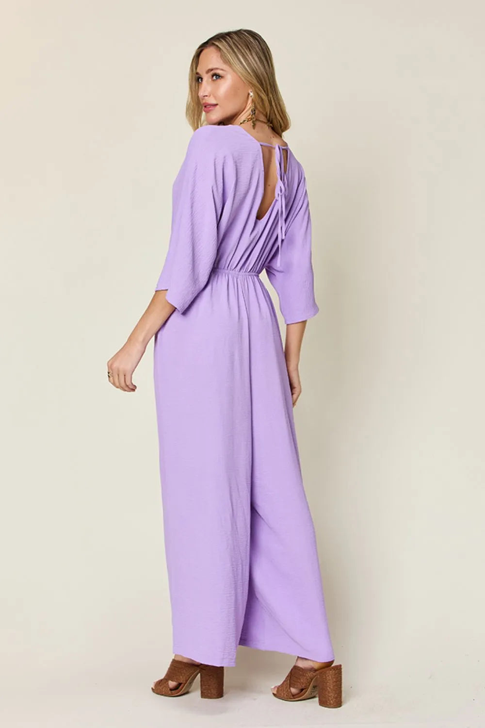 Double Take Full Size Surplice Wide Leg Jumpsuit with Pockets back view model looking back, highlighting elegant drape and comfortable fit