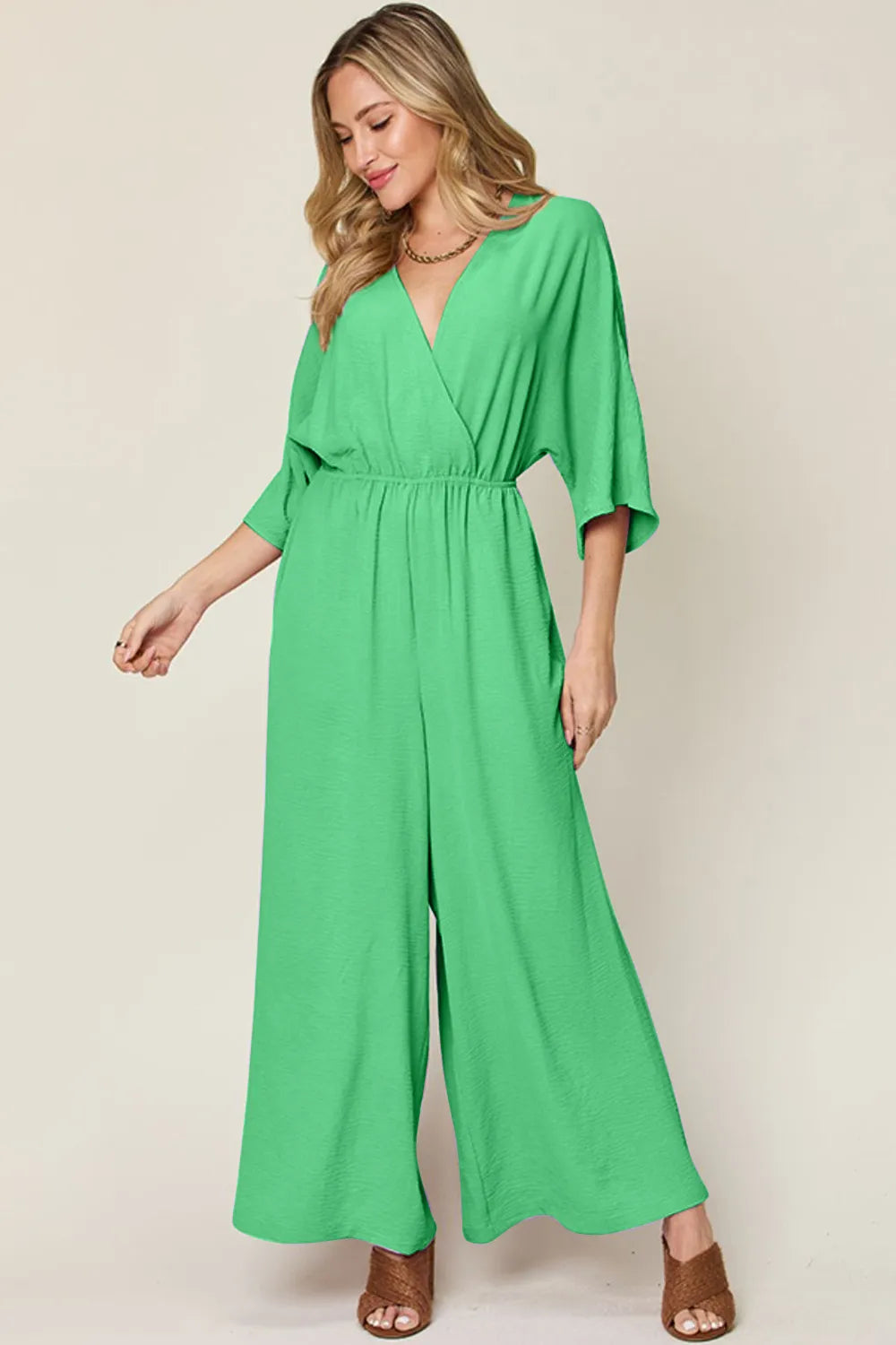 Double Take Full Size Surplice Wide Leg Jumpsuit with Pockets front view model posing, showcasing surplice neckline and relaxed wide legs