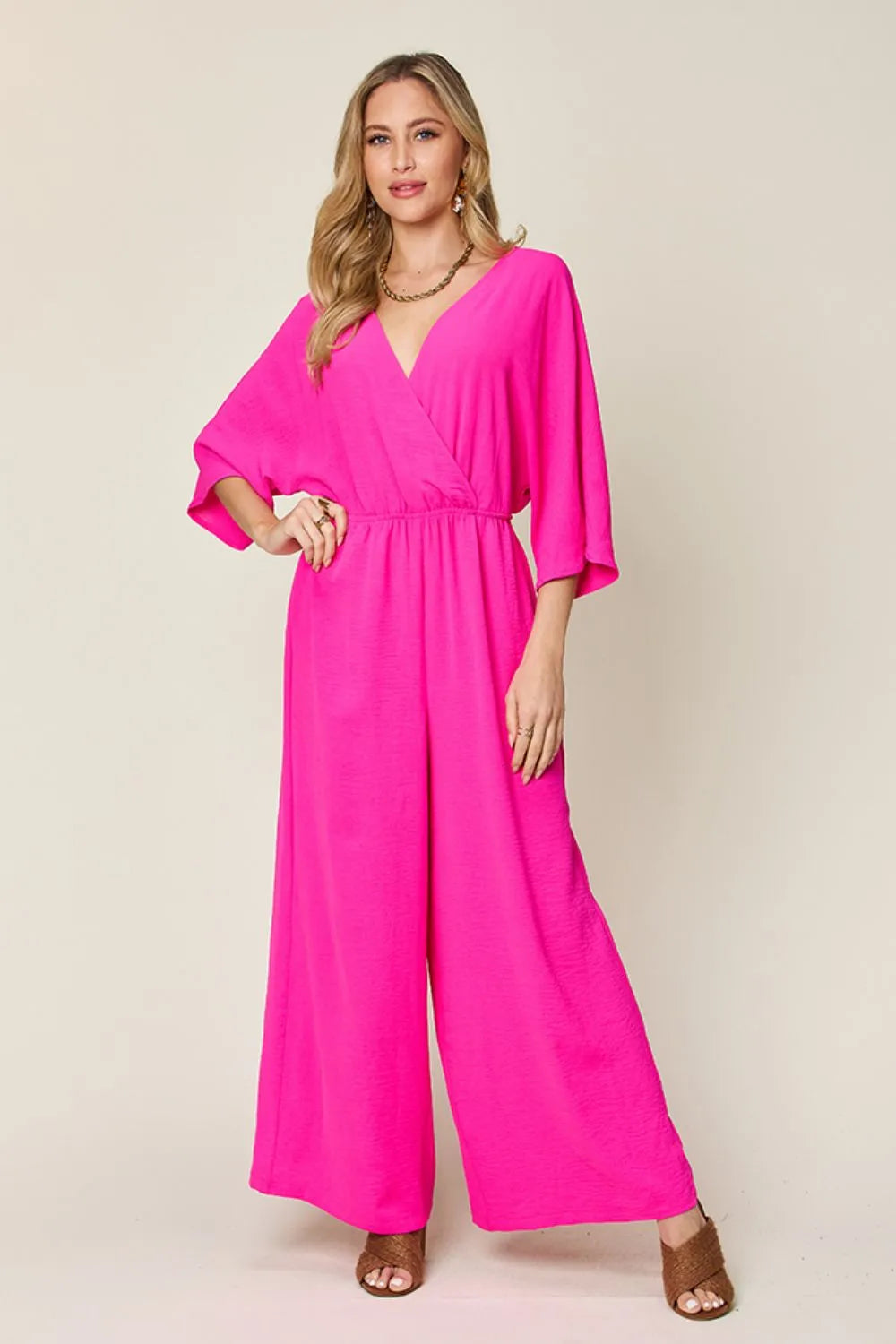 Double Take Full Size Surplice Wide Leg Jumpsuit with Pockets front view model hands in pockets, showing functional side pockets and comfortable fit