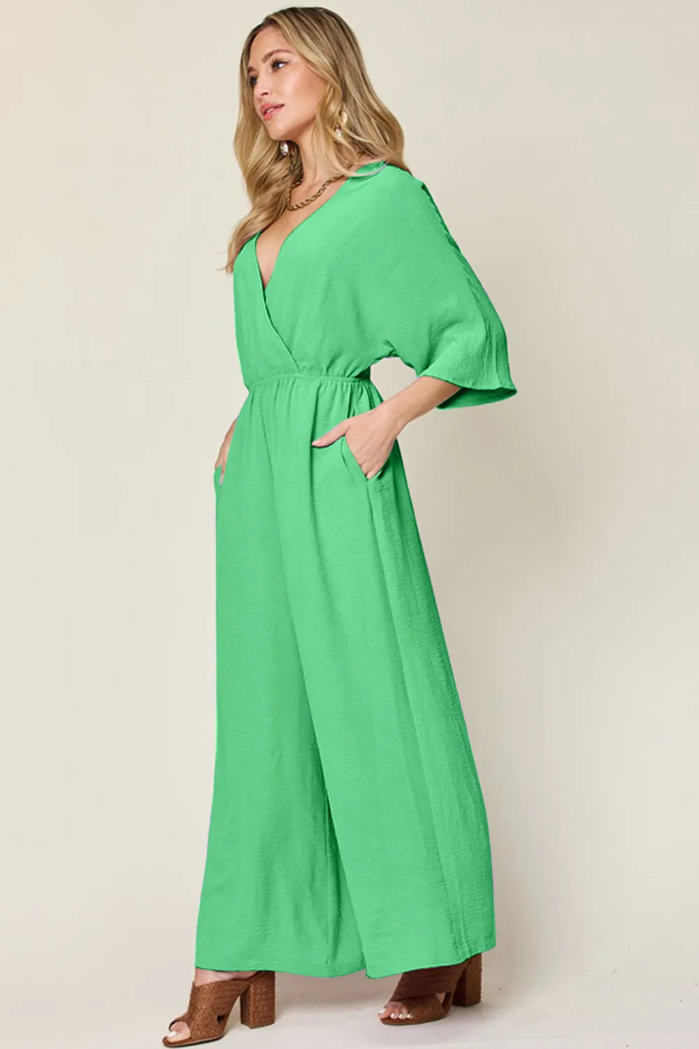 Double Take Full Size Surplice Wide Leg Jumpsuit with Pockets side view model profile, highlighting surplice wrap detail and flowing fabric