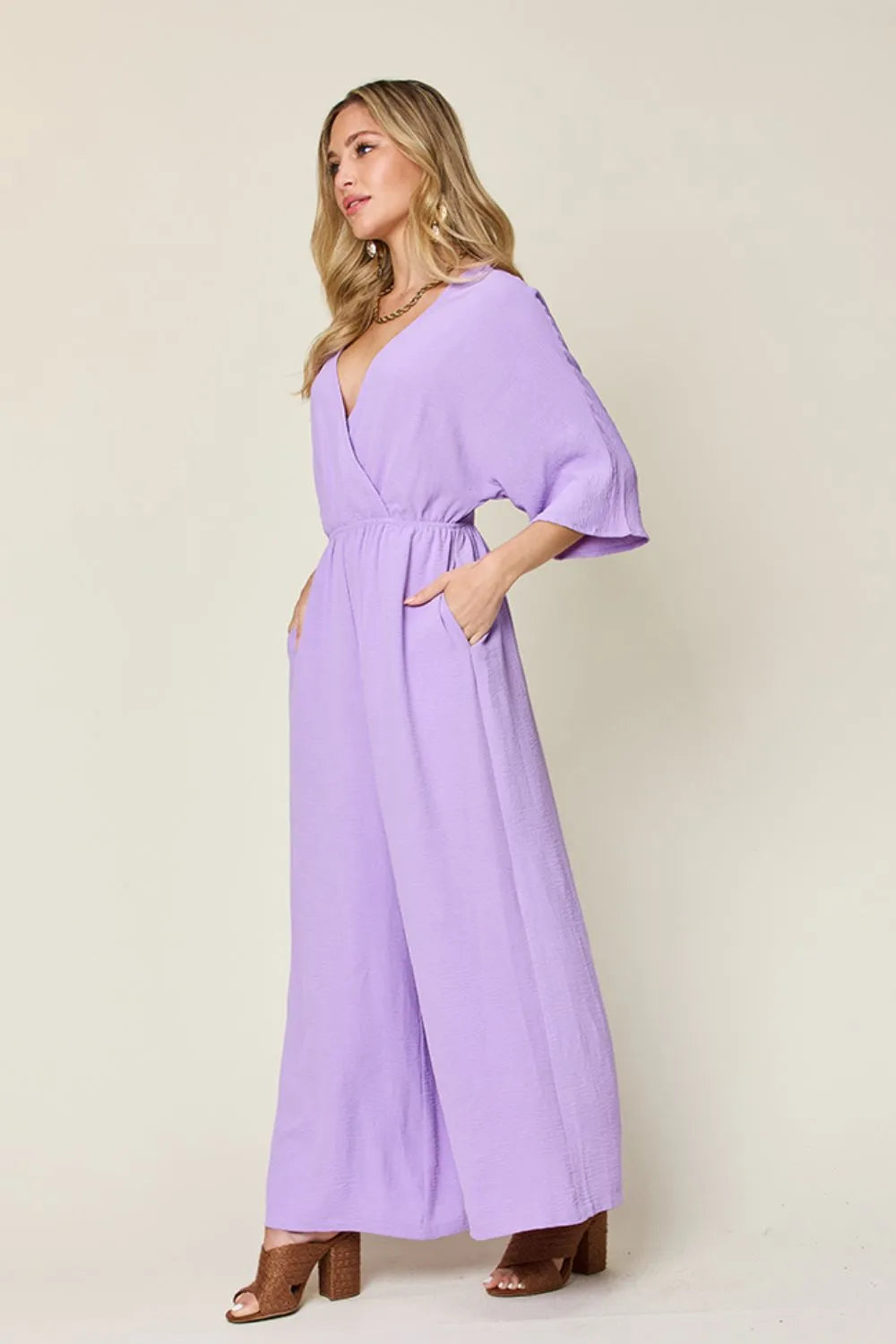Double Take Full Size Surplice Wide Leg Jumpsuit with Pockets side view model walking, showcasing wide leg fullness and elegant drape