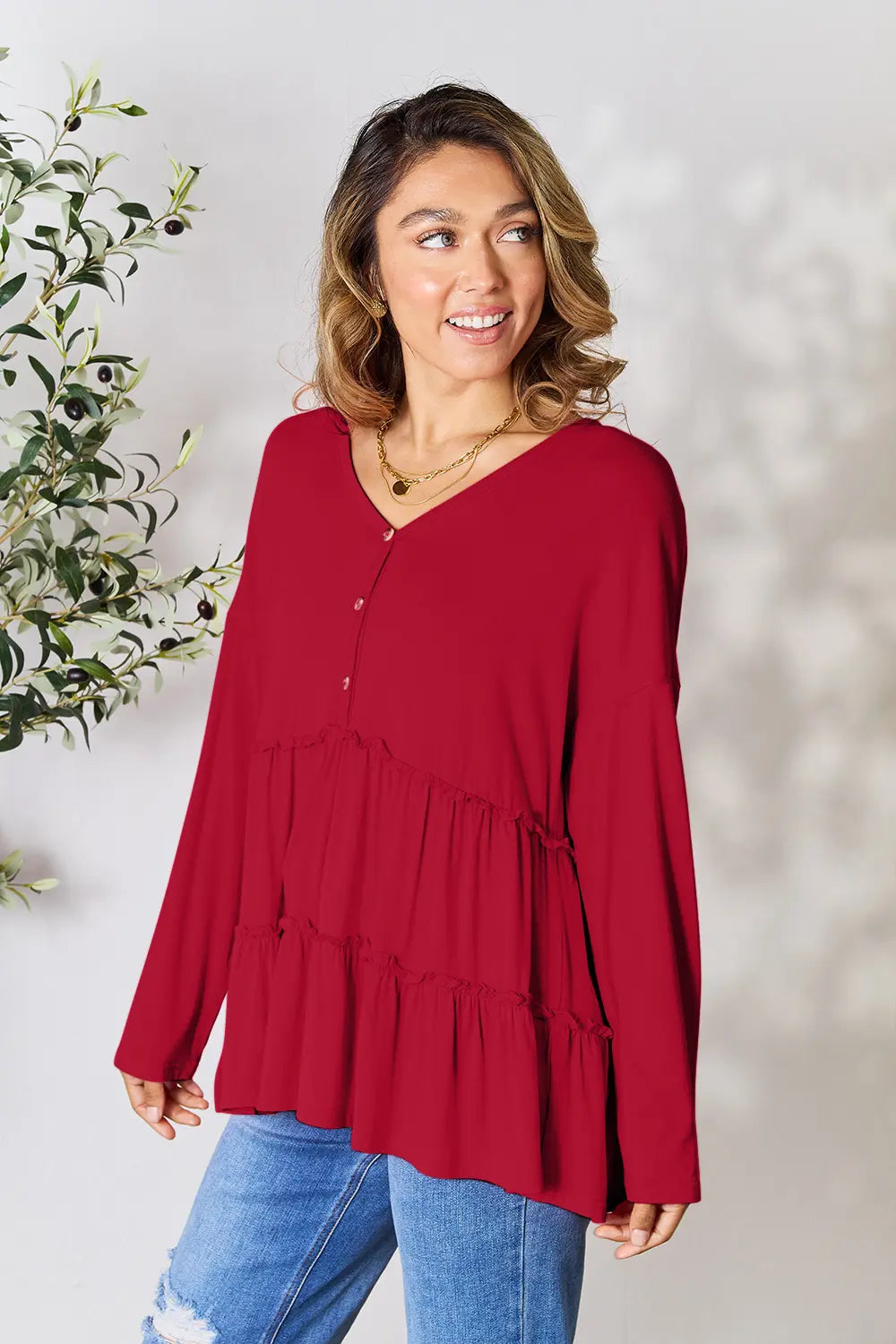 Side view of Double Take half button long sleeve ruffle hem blouse showing ruffle hem.
