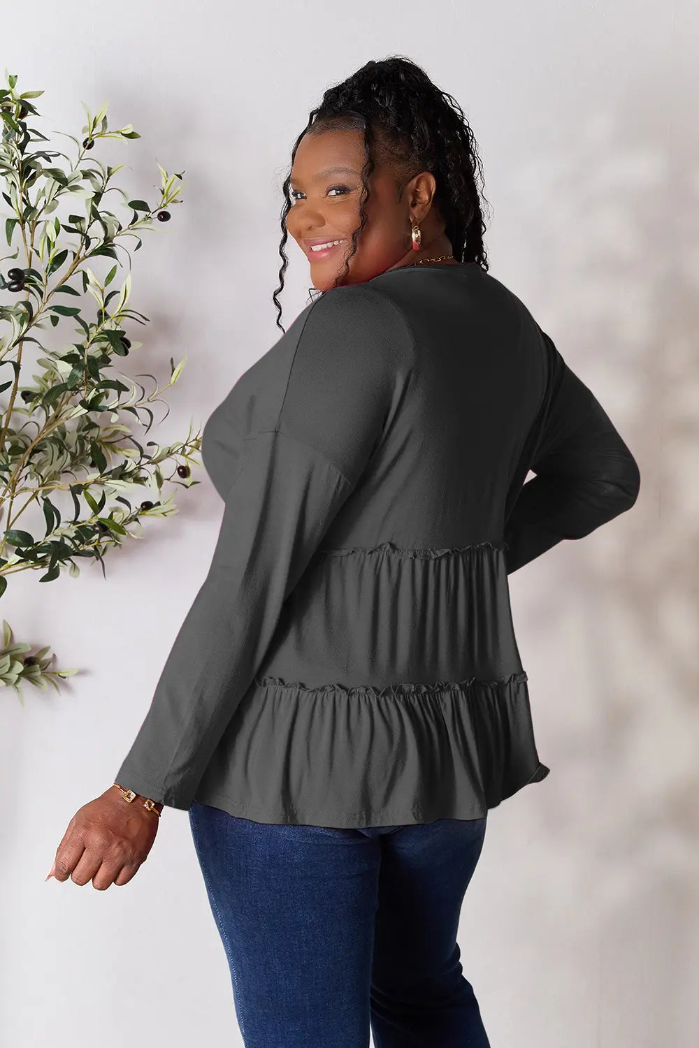 Back view of Double Take half button long sleeve ruffle hem blouse showing flowy hem.
