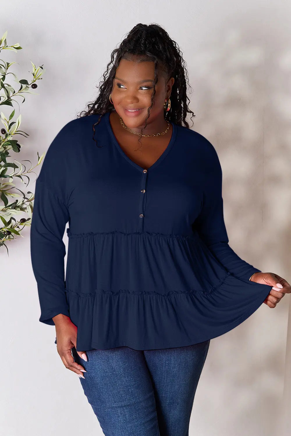 Full-length front view of Double Take half button long sleeve ruffle hem blouse on model.
