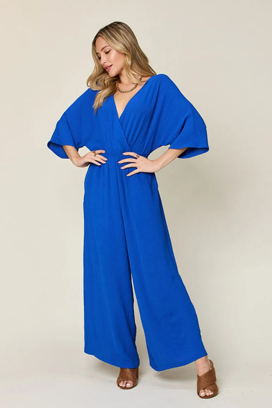 Double Take Full Size Surplice Wide Leg Jumpsuit front view model standing, flattering wrap front with pockets
