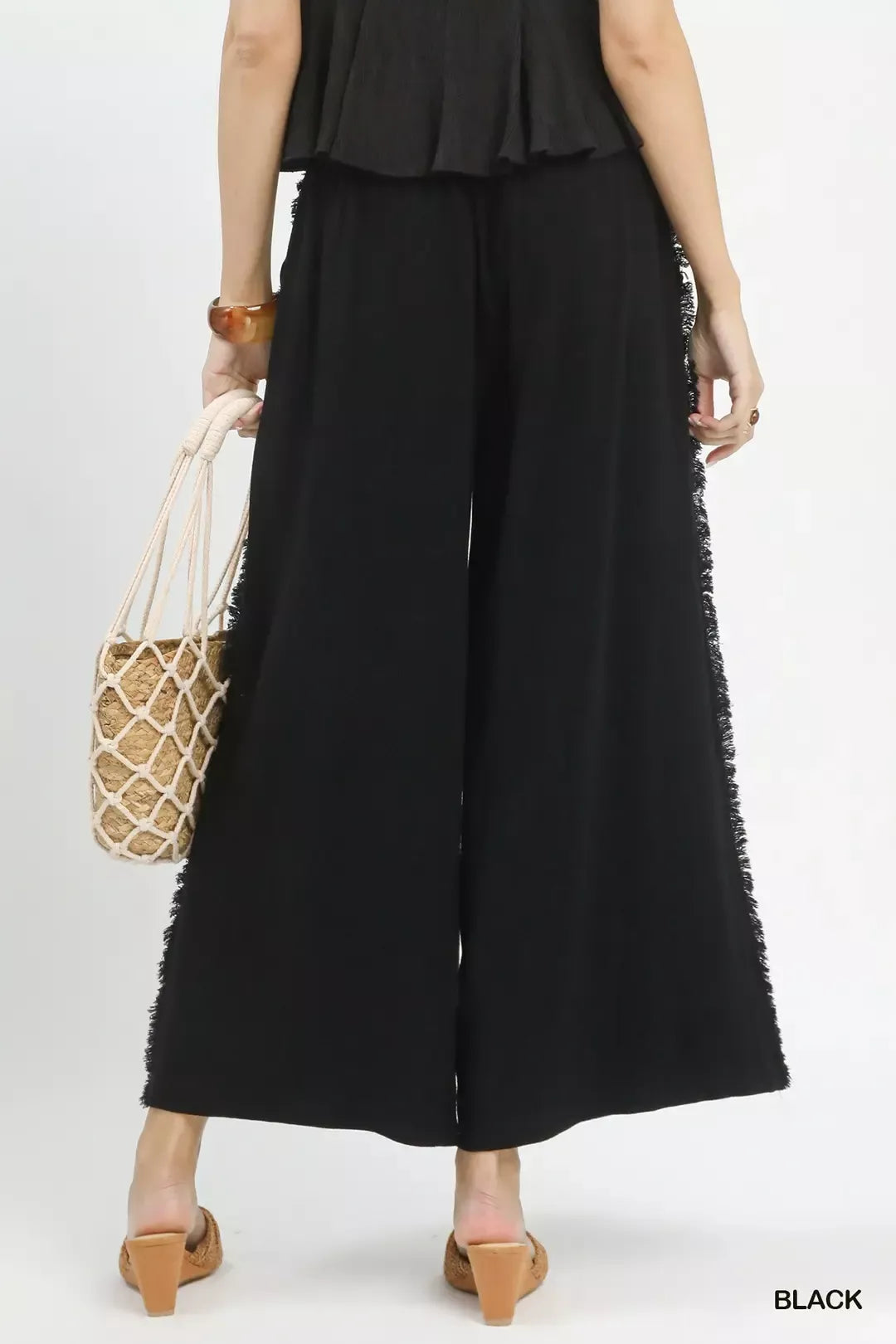 Back view of women's linen frayed wide leg pants showing flowy fit and comfortable relaxed summer style
