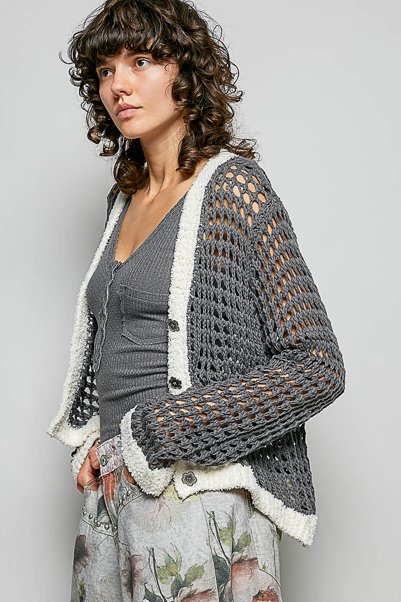 Side view of long sleeve openwork cardigan showing structured fit and Berber neck detailing with floral metal buttons.