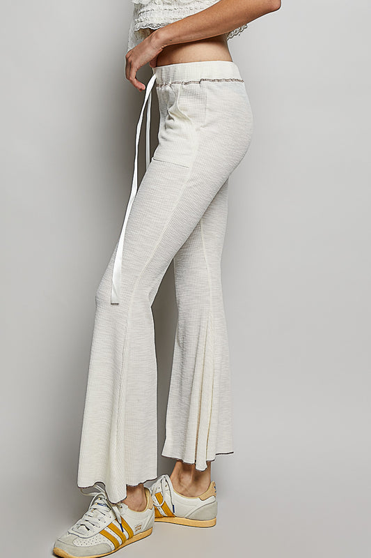 Side view of POL textured ribbed knit flare pants showing the flattering flare leg silhouette and high rise fit on a female model.
