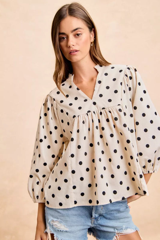 Woman with hands on hips wearing v neck corduroy blouse with all over polka dots, quarter sleeves, soft fine wale corduroy texture visible, fitted bust
