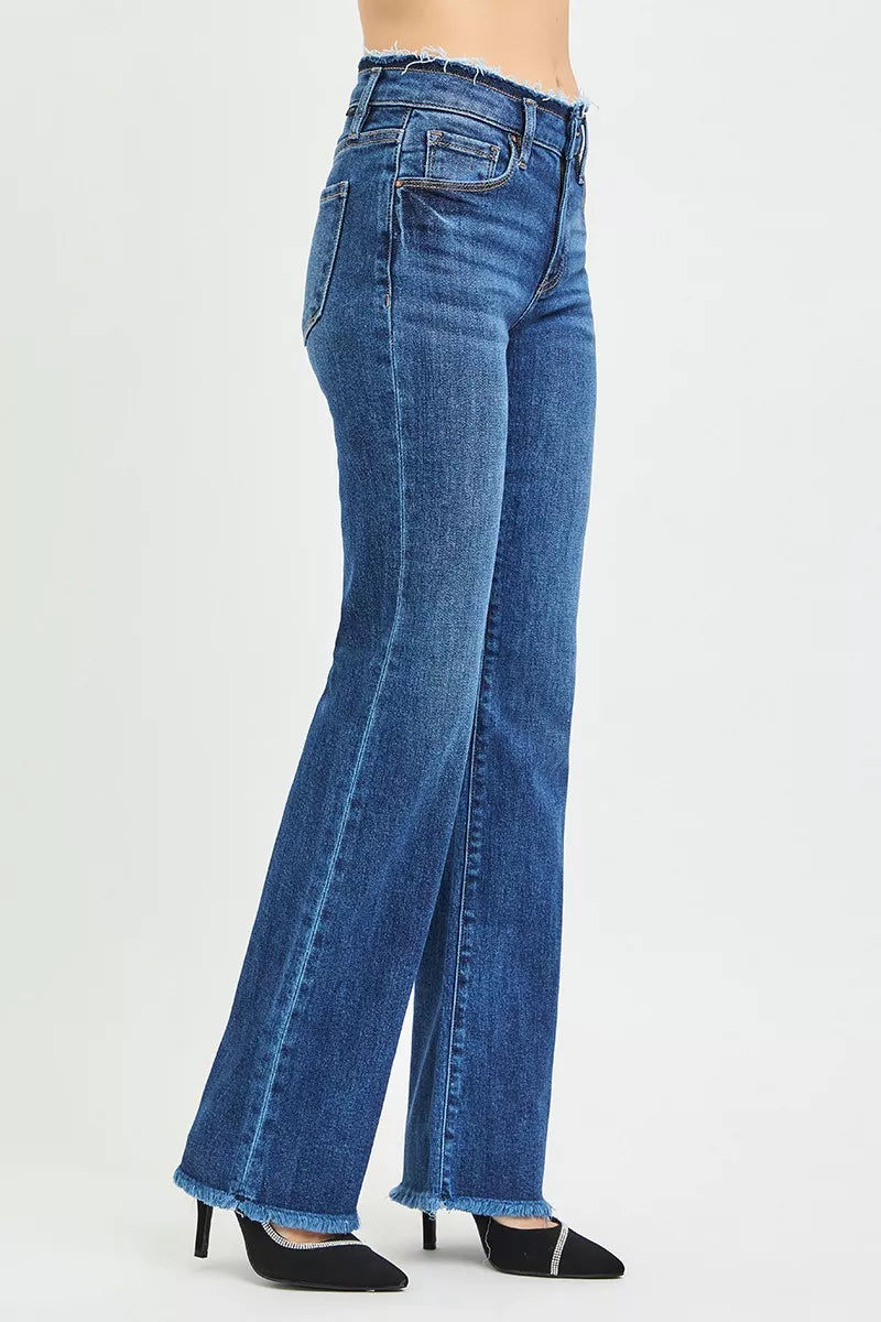 RISEN mid rise bootcut jeans side view, model standing sideways, bootcut leg shape visible, raw hem at ankle, frayed waistband edge detail