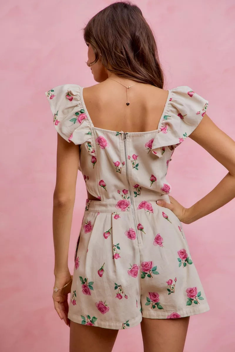 SO ME floral denim cutout ruffle romper model standing facing back, back view of denim romper with floral print, cutout design, and ruffle accents