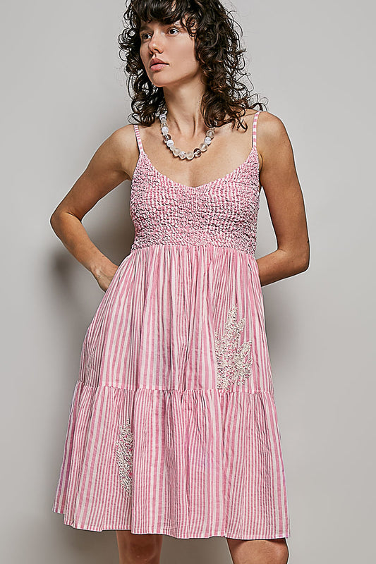 Woman wearing striped smocked mini dress with spangle embroidery front view showcasing V-neck and flowy silhouette

