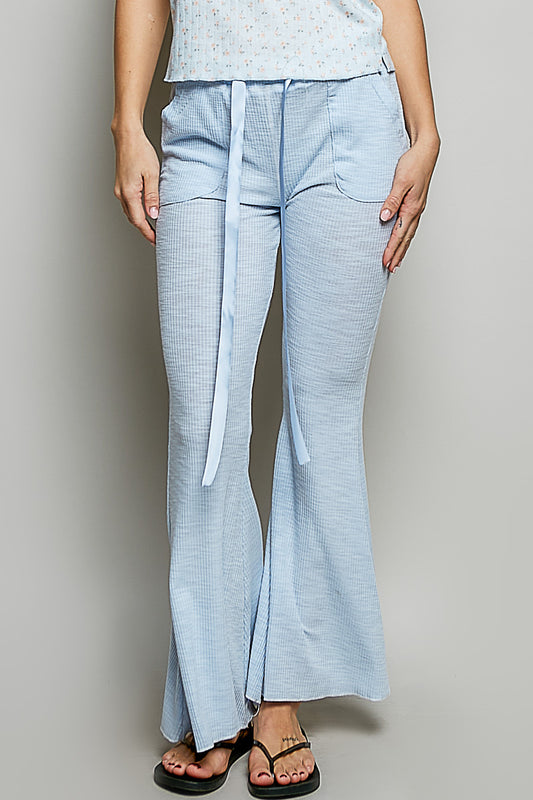Woman wearing light blue textured ribbed knit flare pants front view showcasing drawstring waist and relaxed fit