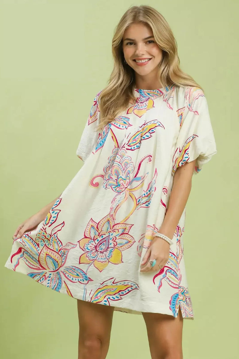 Front view of Umgee boho floral mini dress. Lightweight summer dress with pockets. V-neckline, short flutter sleeves, multicolor floral print on cream background. Falls above knee. Loose fit.