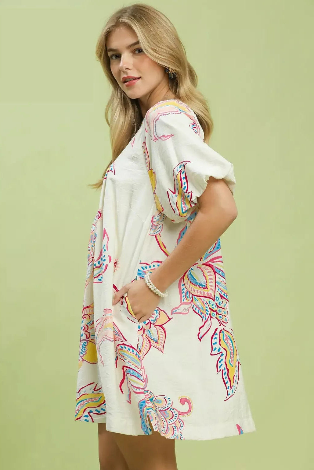 Side view of Umgee boho floral mini dress. Shows relaxed A-line silhouette. Lightweight woven fabric. Short sleeves. Hem hits mid-thigh. Visible pocket detail on right side.