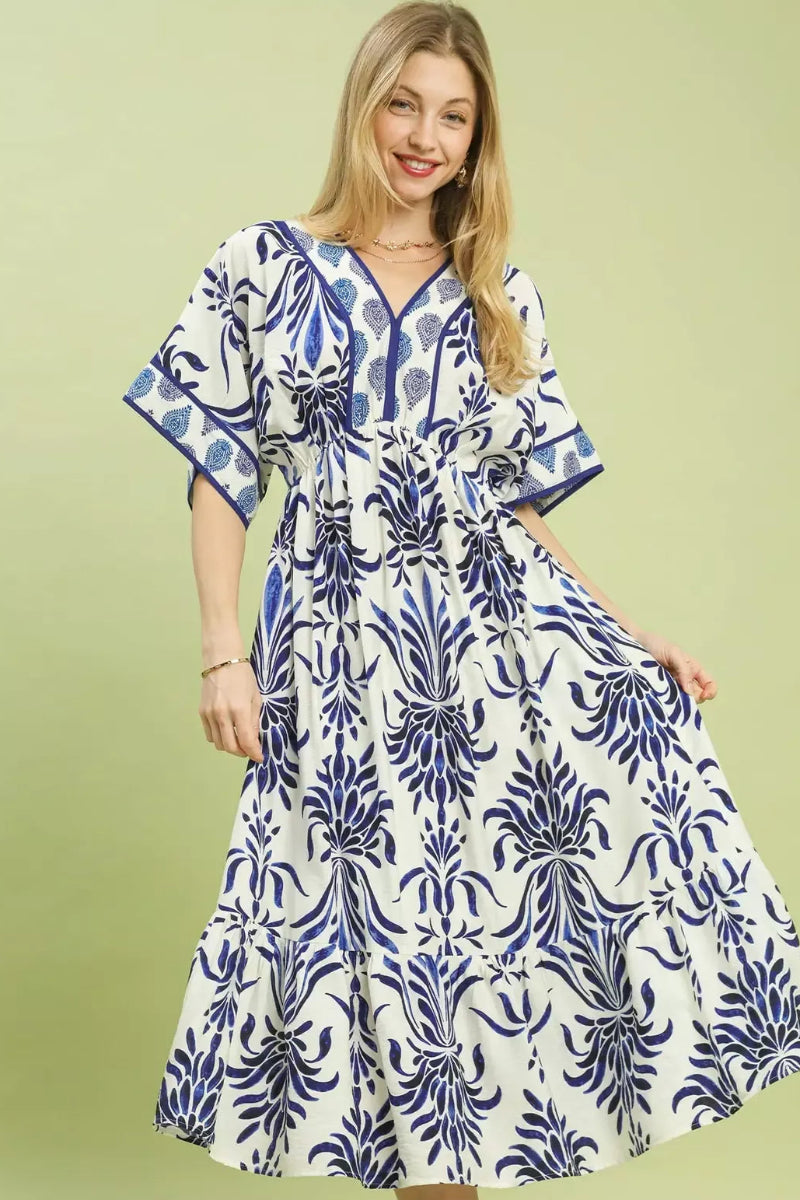 Umgee floral border print midi dress with pockets for women model standing facing front, showing floral border pattern, midi length, pockets, short sleeves or sleeveless fit