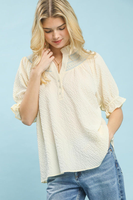Woman wearing textured Henley blouse with lace shoulder panels and ruffle cuffs front view showcasing intricate bullion stitch details