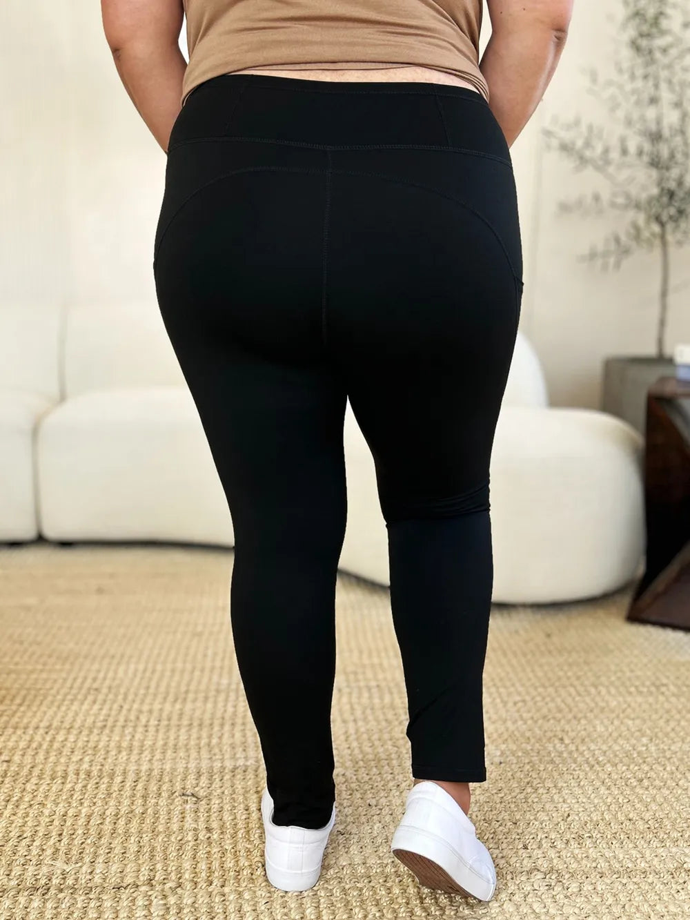 Model in deep squat position showing back of high rise leggings, fabric opaque and non-see-through, wide band stays in place