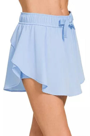 Zenana soft woven active skorts 2-in-1 lightweight model standing facing side, side view of active skorts with flowy overlay and inner shorts
